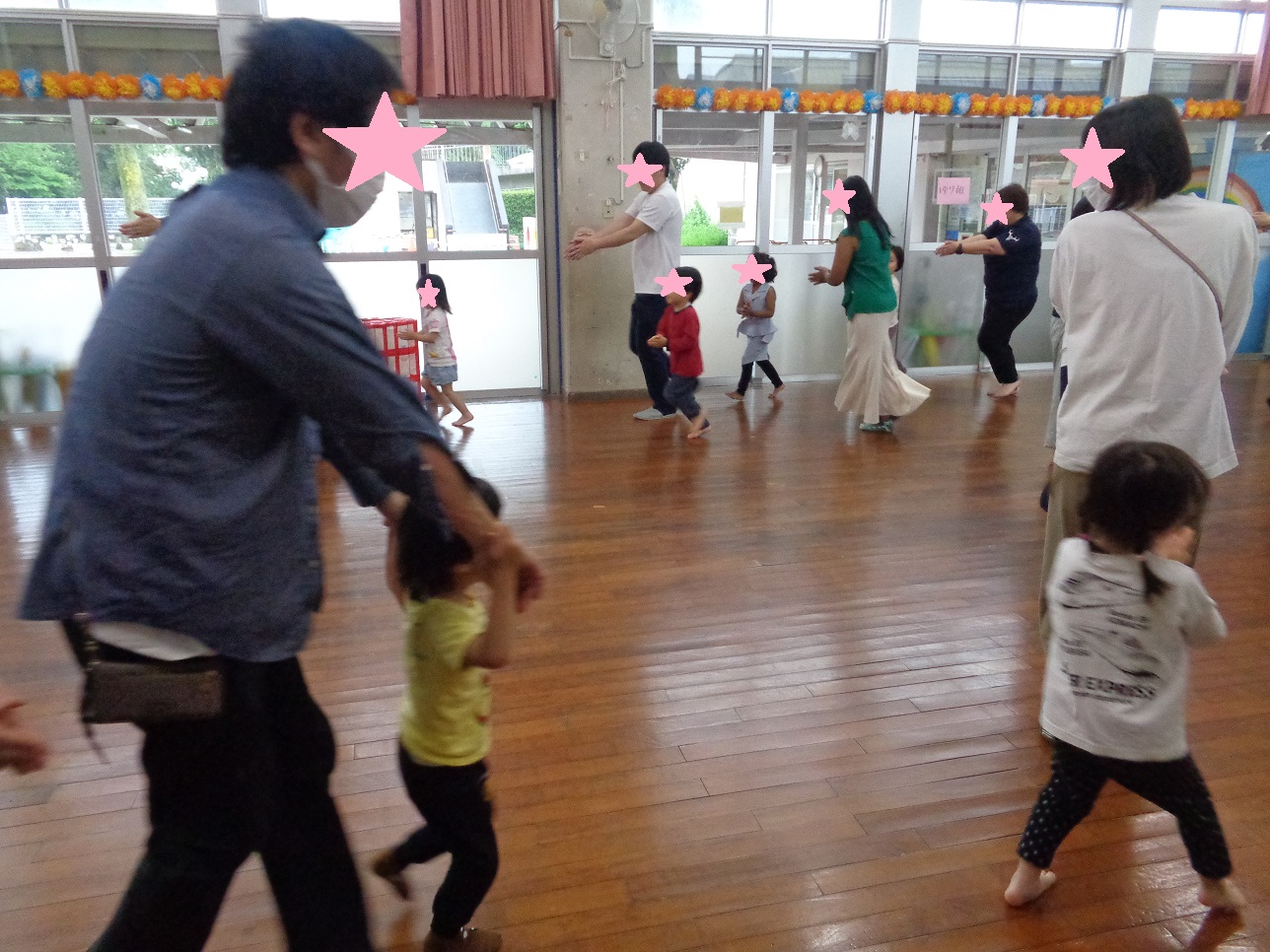 親と子どもたちが板のホールで裸足で走り回っている。