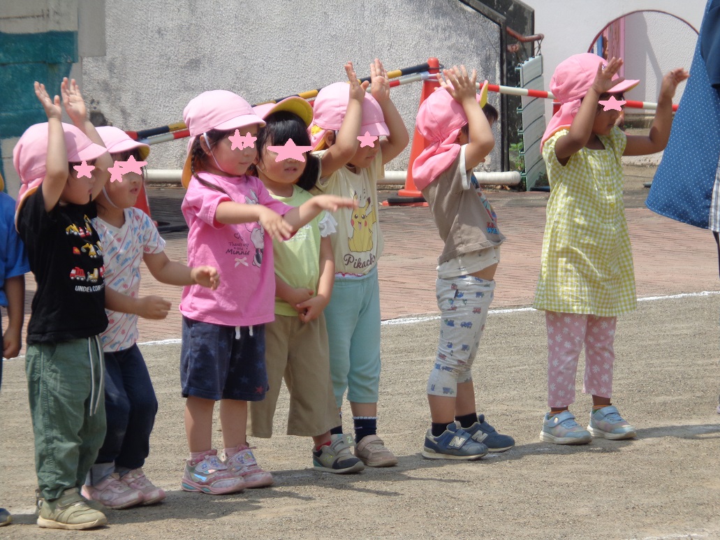 両手を上にあげたり前に伸ばして立っている子どもたち