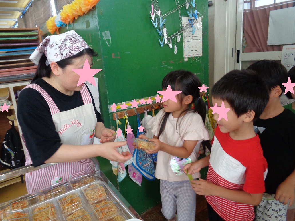 パック詰めした焼きそばを大人から子供へ渡している