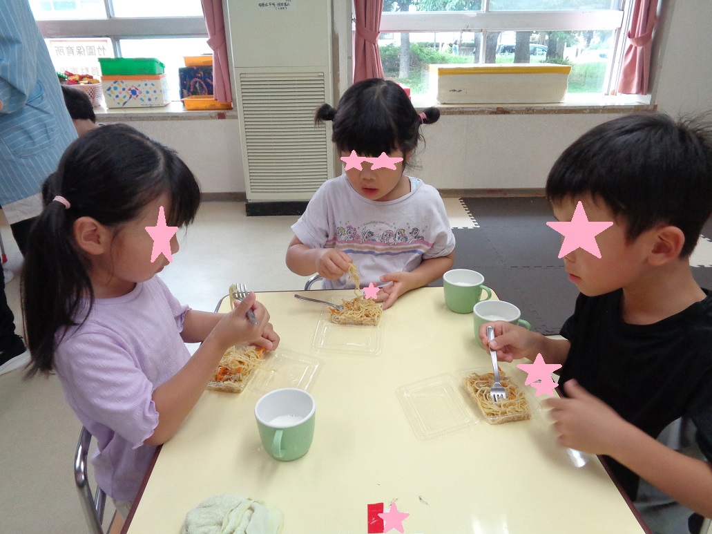 座って焼きそばを食べる子どもたち