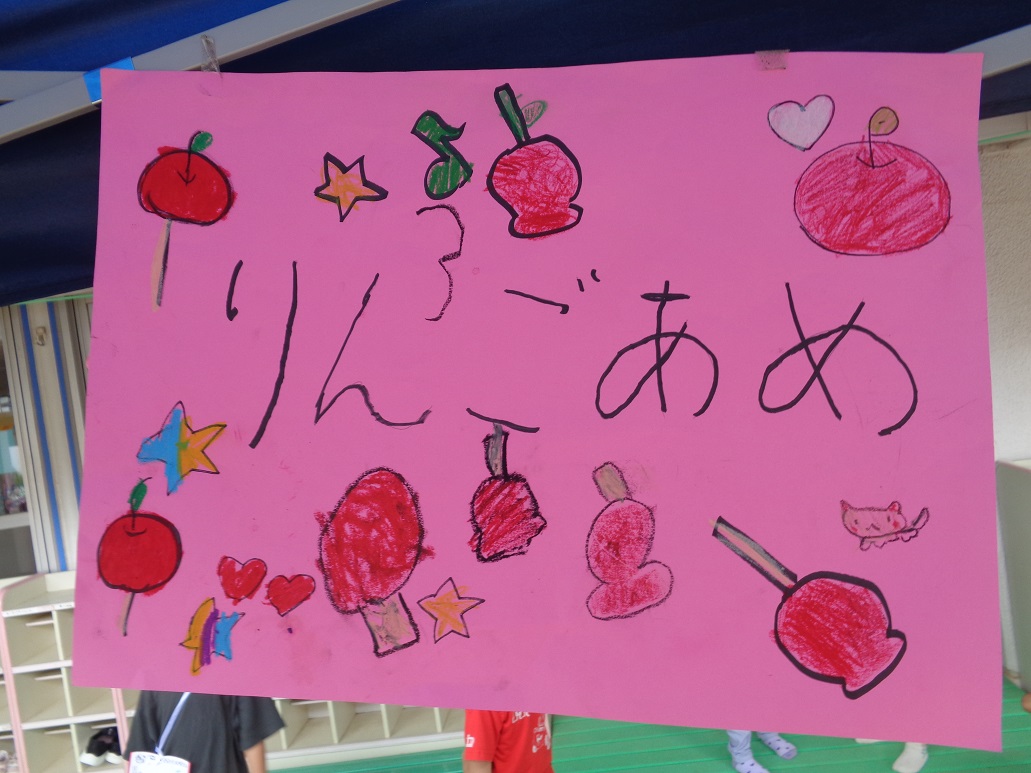 りんごあめとピンク色の画用紙に文字とイラストが描いてある