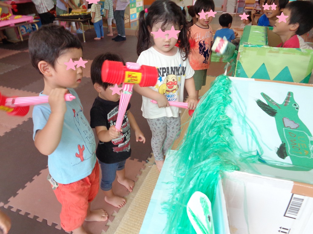 ハンマーを持ちみどりのスズランテープの前に立ち子どもたち