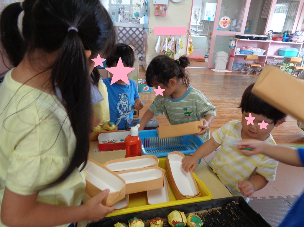 子どもたちが手に箱を持ち手を伸ばし選んでいる。