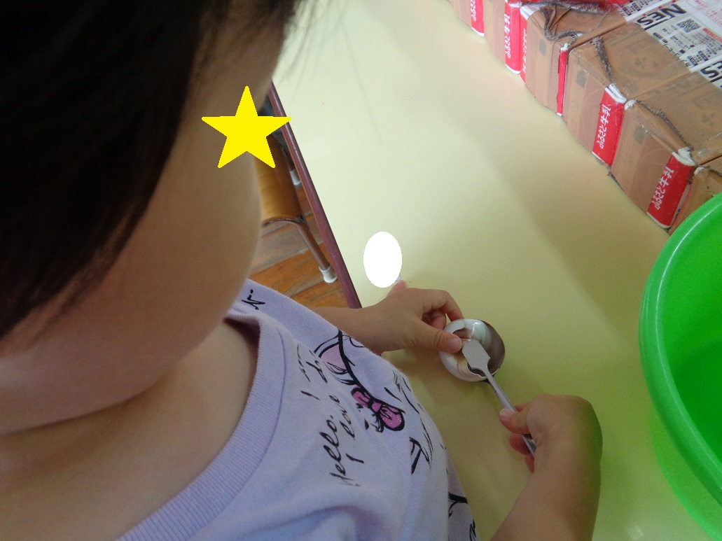 子どもが貝殻にスプーンをのせている