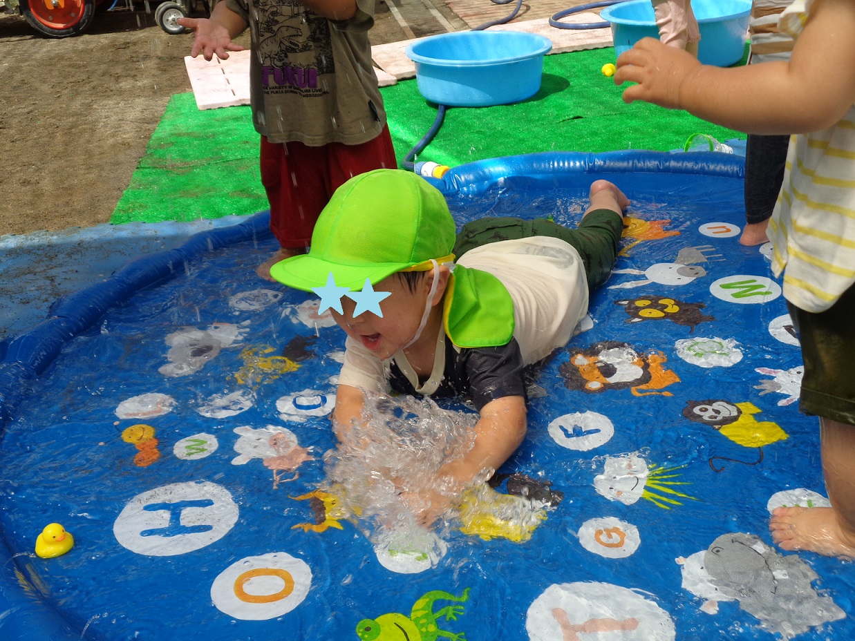 水を張ったビニールシートにうつぶせになり水しぶきを上げている子ども