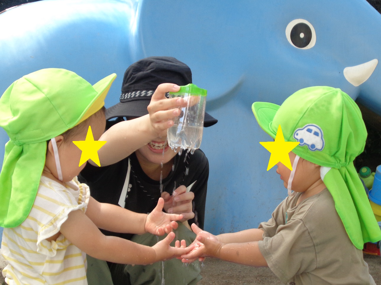 ペットボトルの底から水がぽたぽた落ち、手に平で触ろうとしている子ども