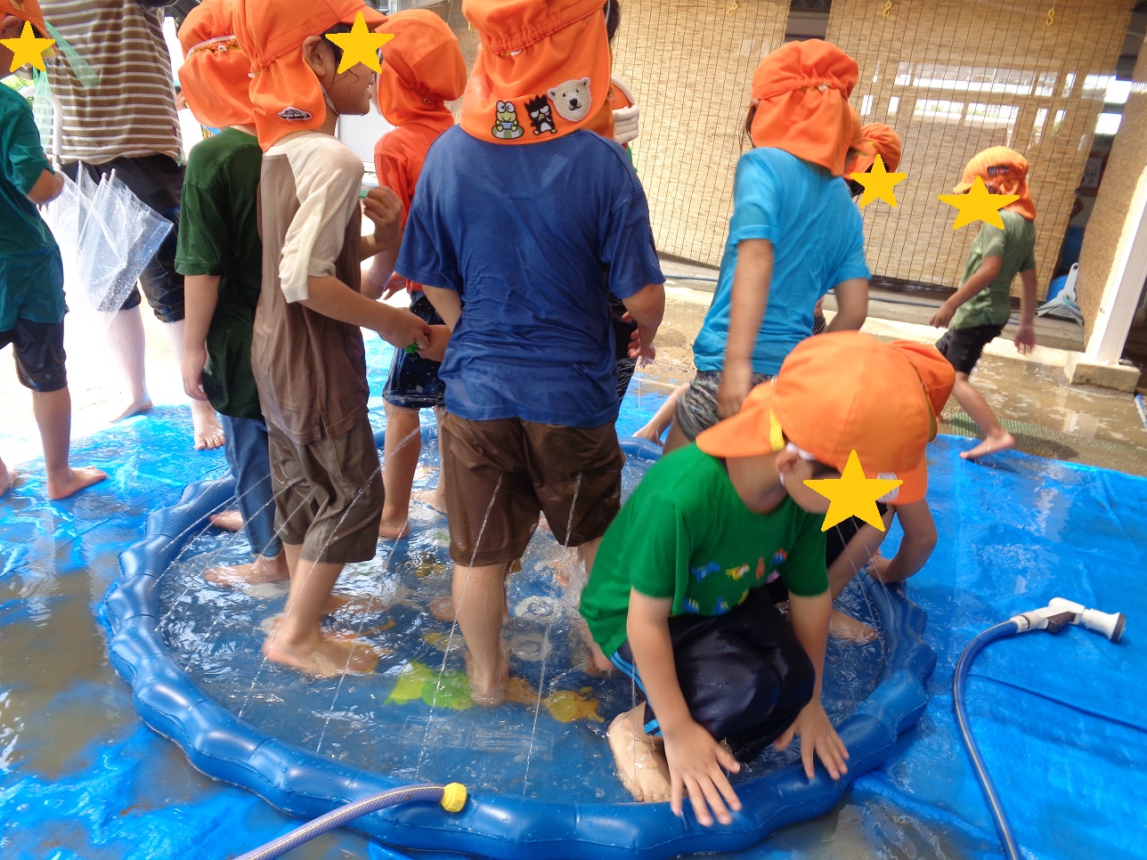 青色のビニールの周りから水が出ている、くるぶしほど溜まった水の中に子どもたちが立っている