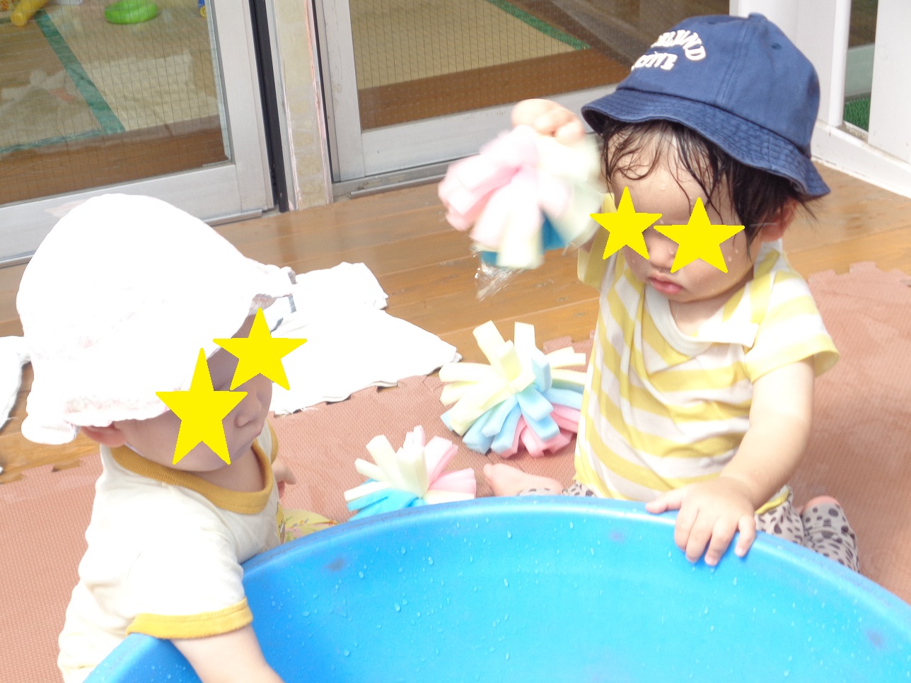 タライのそばでこどもが手にひらひらのボールのようなものを持ちあげている