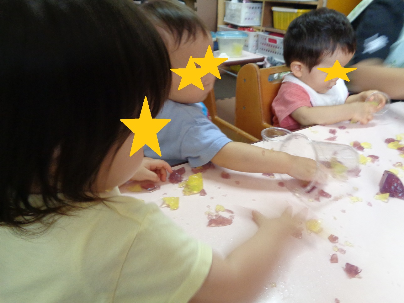 子どもたちがテーブルの上に手を伸ばしたりコップをもっている