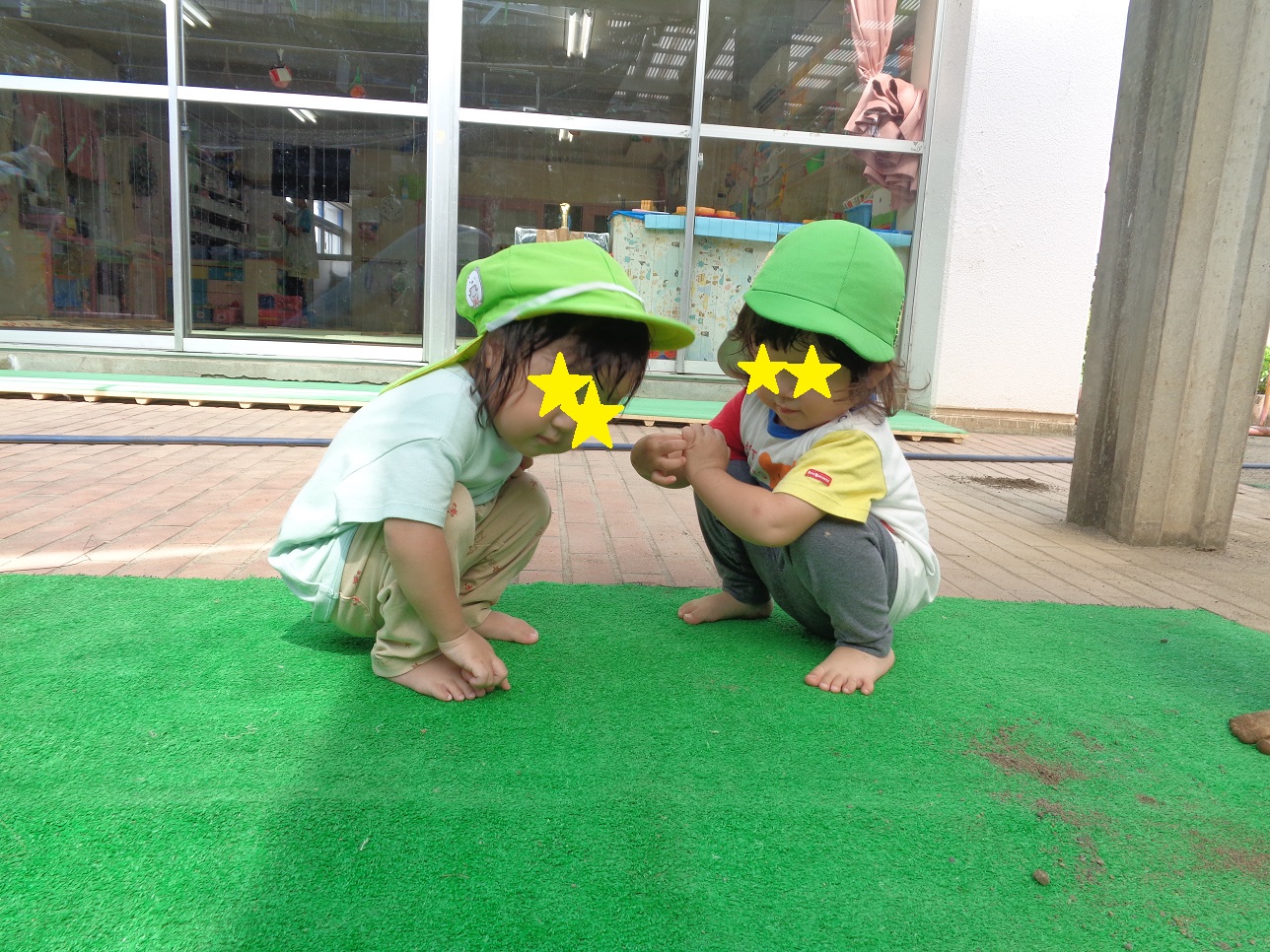 こどもがしゃがんで地面を二人で見ている