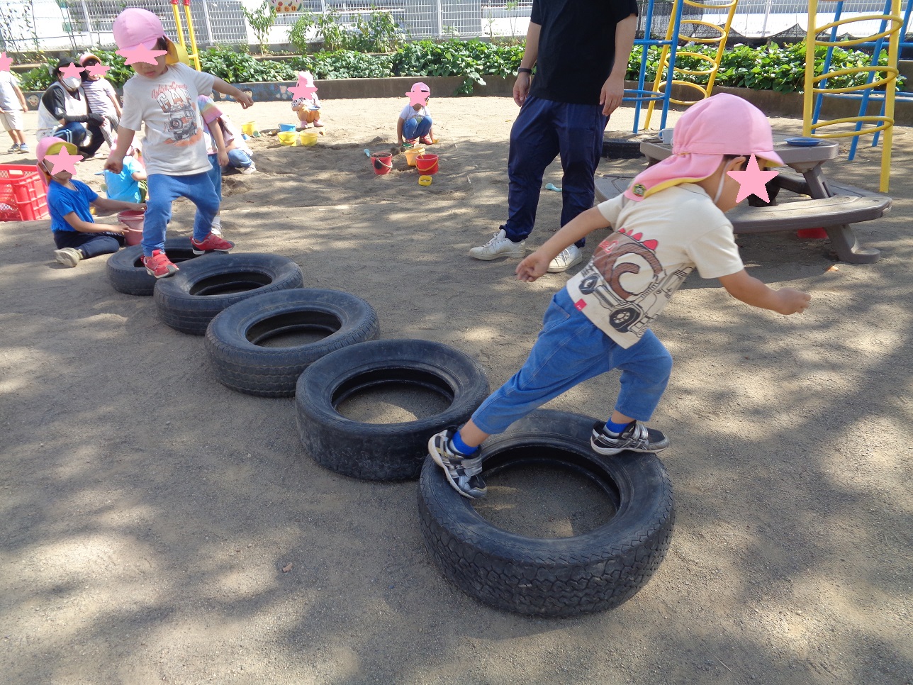 タイヤを地面に並べてその上を子どもが歩いて渡っている