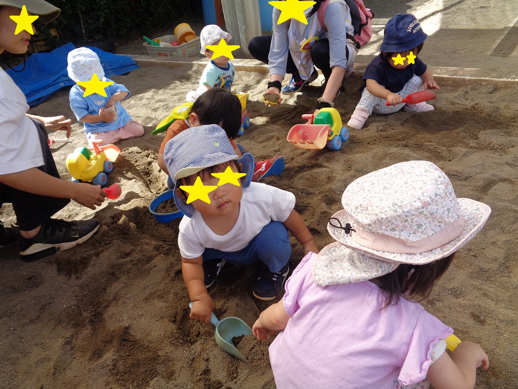 こどもと大人が座ってしゃべるを持ち砂を掘っている