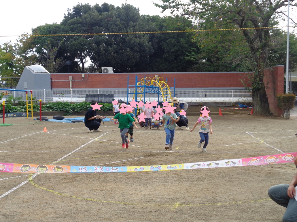 ピンクの帽子をかっぶている子どもがゴールテープに向かってまっすぐ走っている。