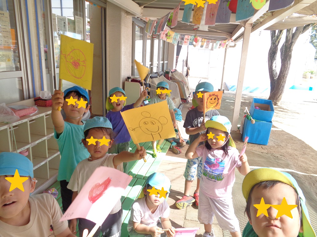 水色の帽子を被った子どもたちが自分で作った旗を振っている。