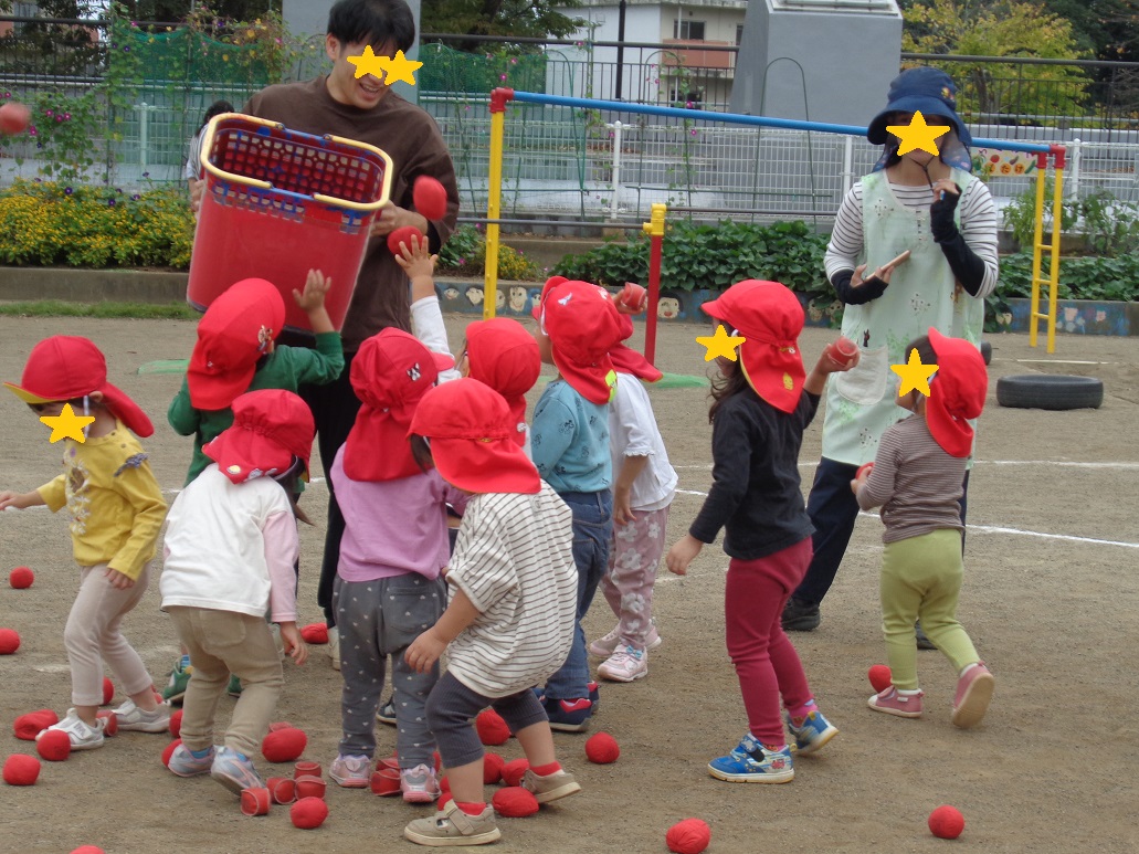 赤い帽子を被った子どもたちが赤い玉を投げている。