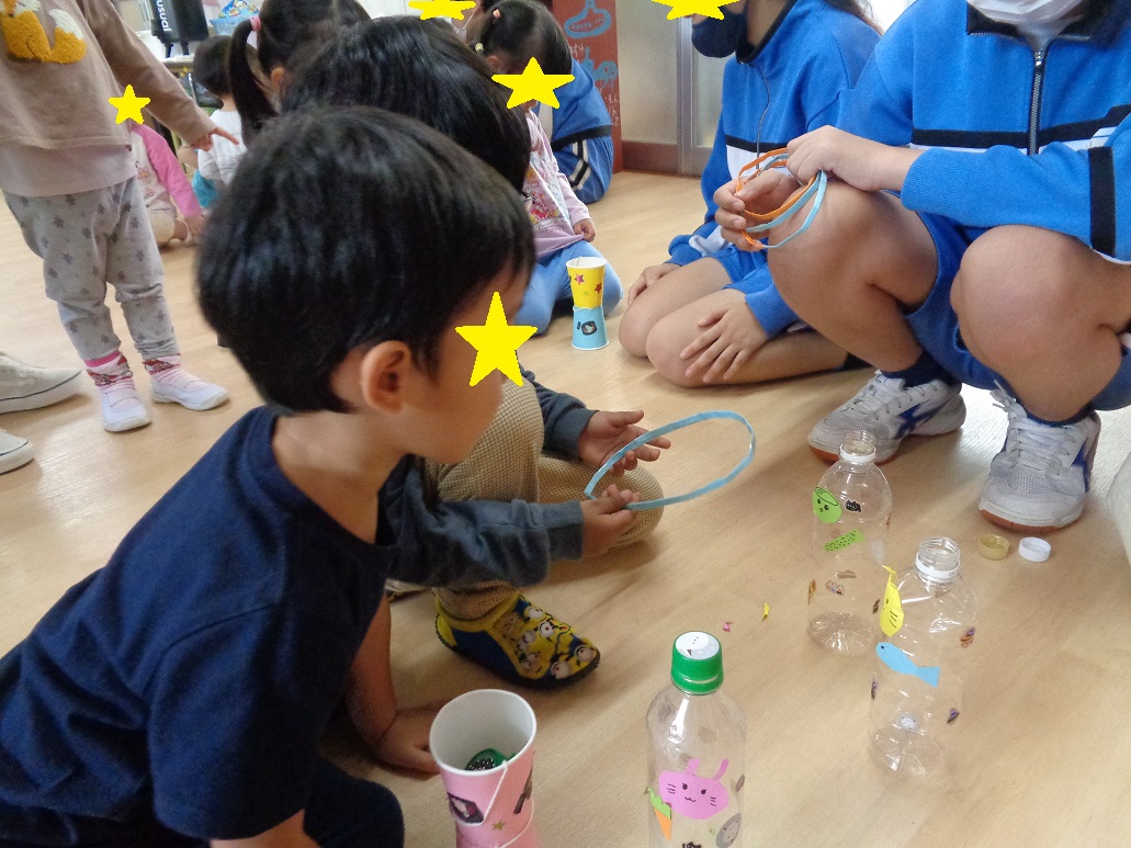 ペットボトルで出来た輪投げに輪を投げようとしている。