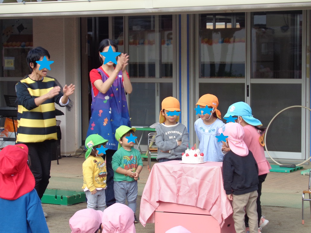 10月生まれの子どもたちがケーキのろうそくを消している。