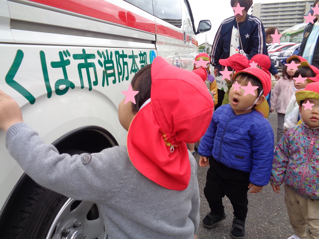 赤い帽子を被った子どもたちが救急車を見ている