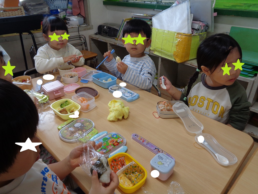 4歳の子どもがスプーンやお箸を使ってお弁当を食べている