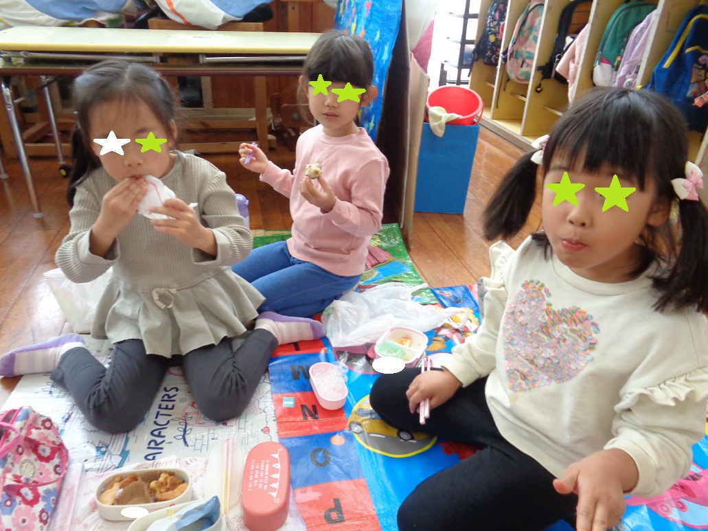 6歳の子どもがシートを広げてその上でお弁当を食べている