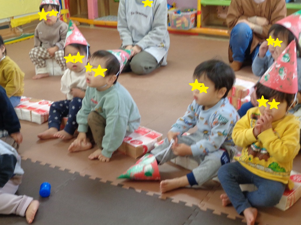 スタンプで飾りつけをした赤い帽子をかぶった子どもがお話を聞いている