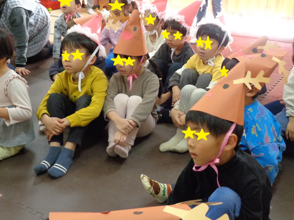 サンタクローズやトナカイの帽子を被った子どもが話を聞いている