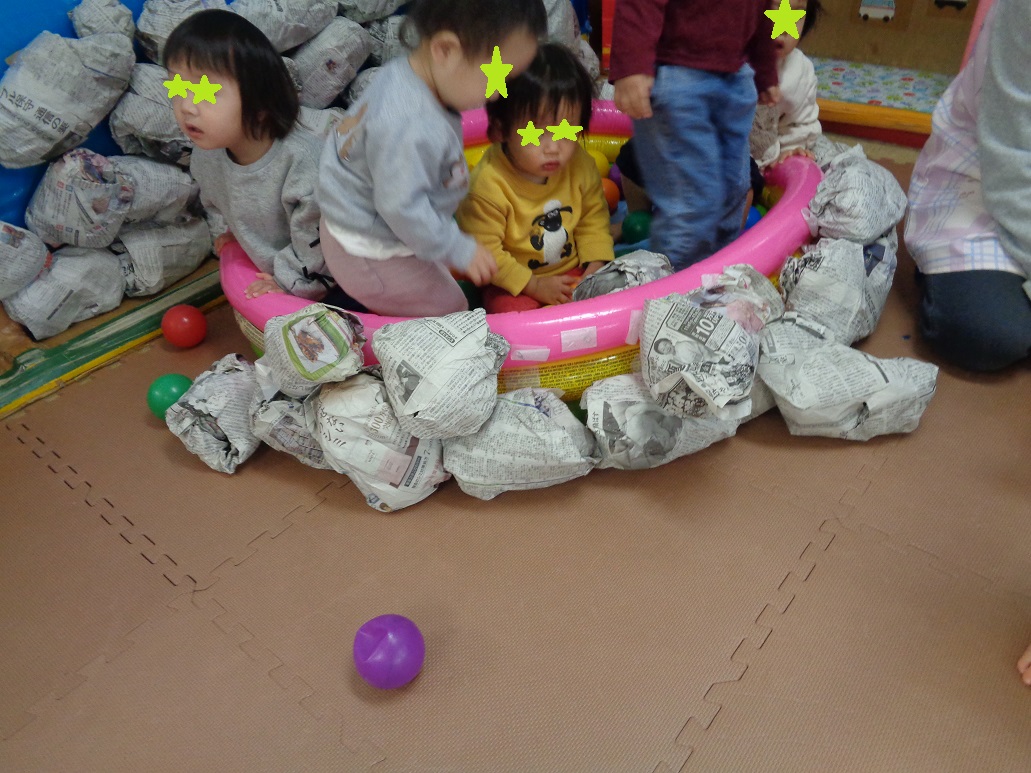 ビニールプールに貼った新聞紙を岩に見立てた岩風呂に入る子どもたち