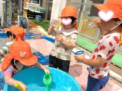 容器から水を移し楽しむ1歳児