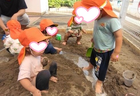 砂場に水を流し感触を楽しむ1歳児