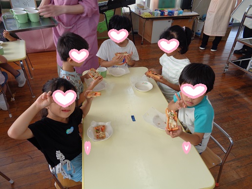 自分で作ったピザを食べて喜ぶ5歳児