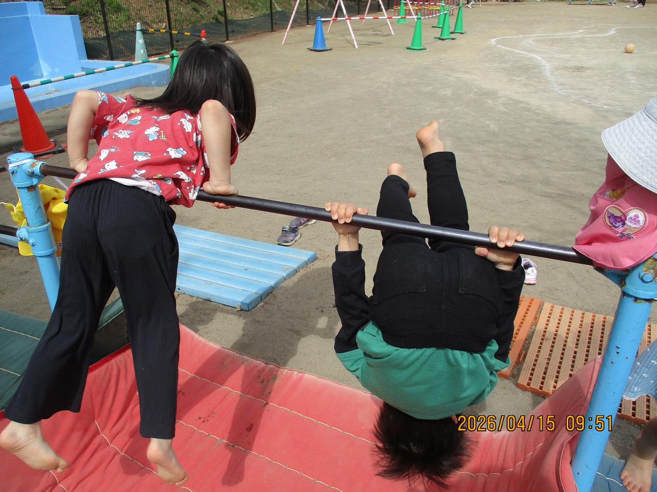 鉄棒にぶら下がっている子どもとおなかを付けている子ども
