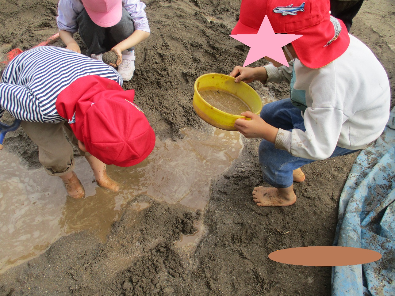 砂場の水たまりでこどもたちが手を入れたりしている