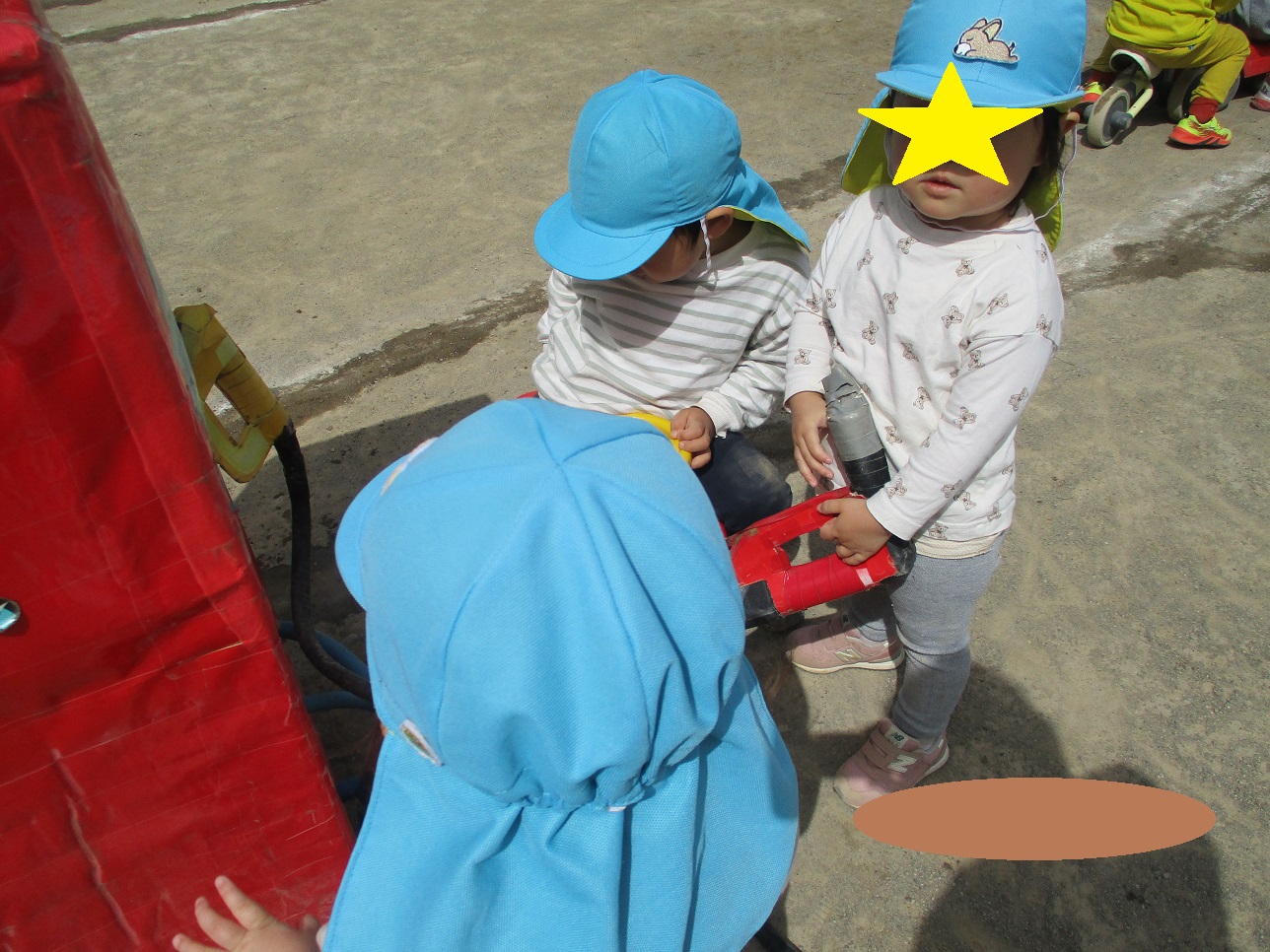 青い帽子をかぶった子供たちがガソリンスタンドごっこをしている