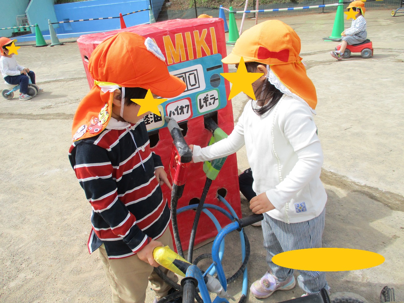 こどもたちがガソリンごっこで三輪車に給油する真似をしている。