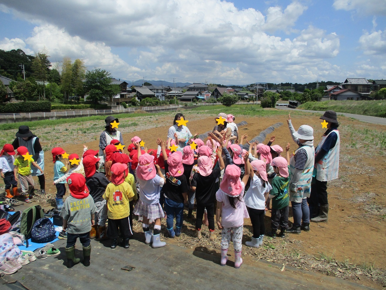 帽子をかぶった子どもたちと大人たち畑で立っている