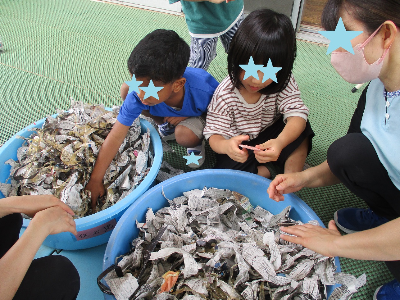 ぎった新聞紙をタライの中に入れ子どもたちが囲んでいる