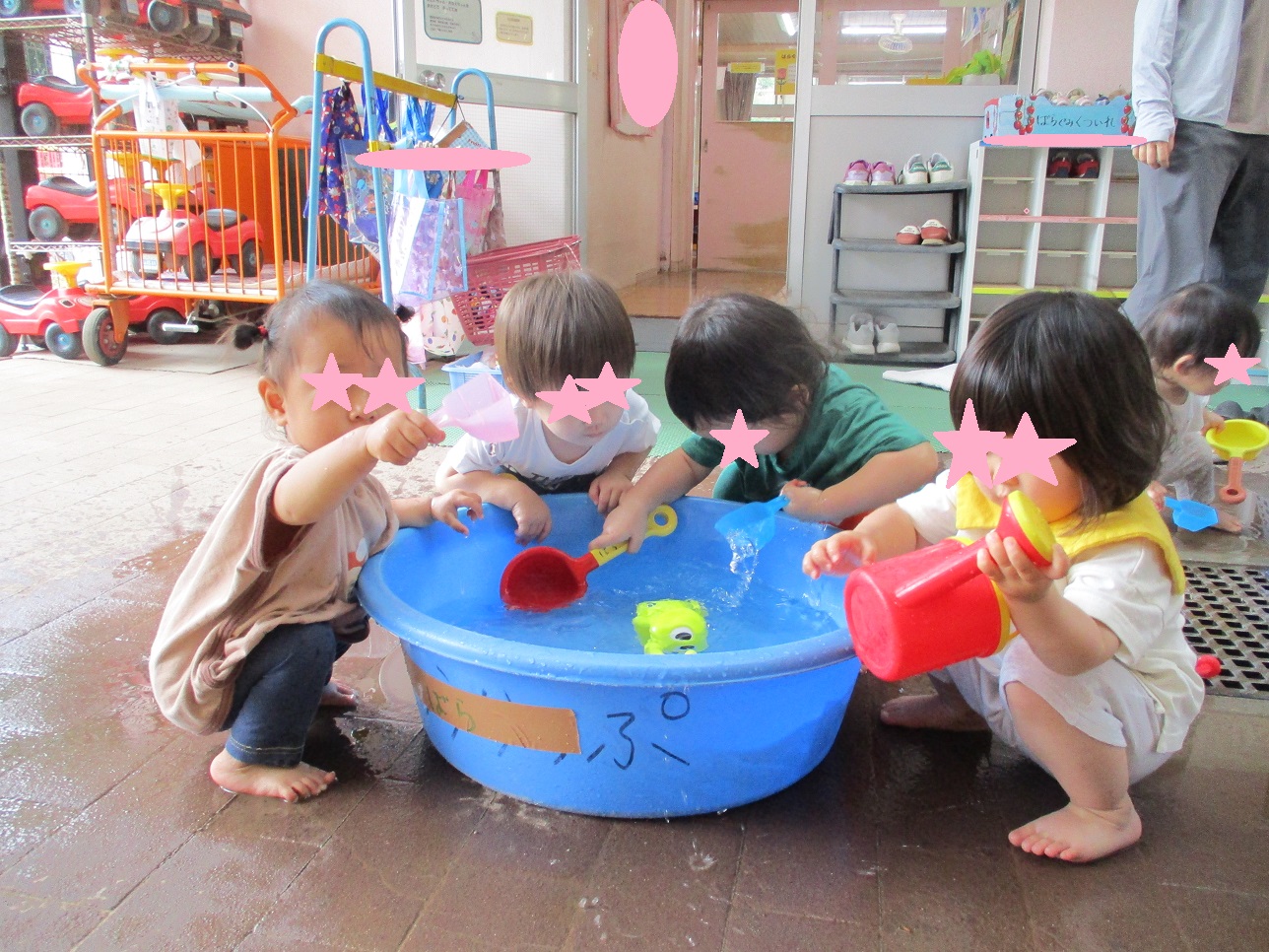 子どもたちがタライの周りに座り水遊びをしている様子