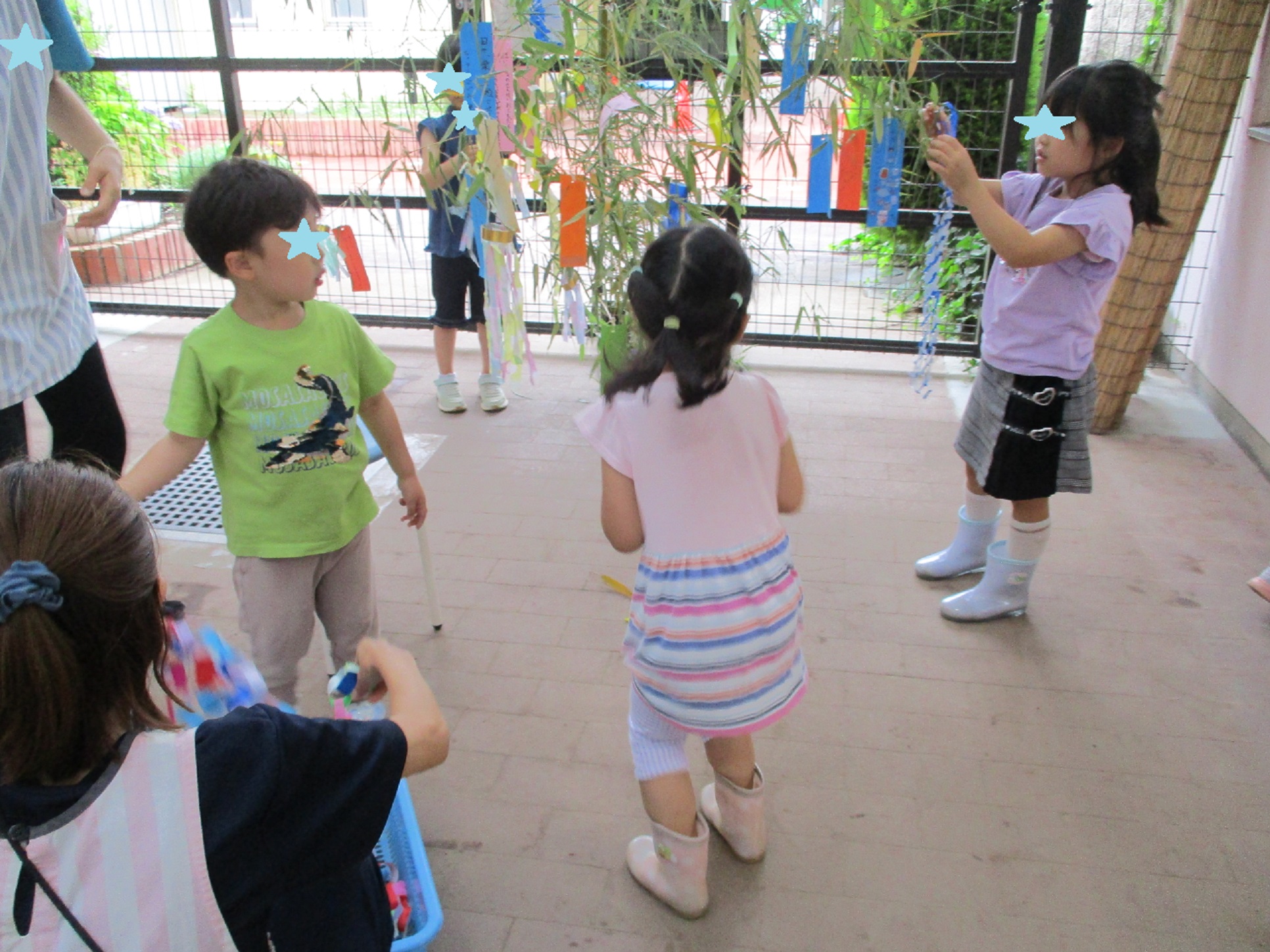 子どもたちが笹の葉に折り紙の飾りつけをしている。